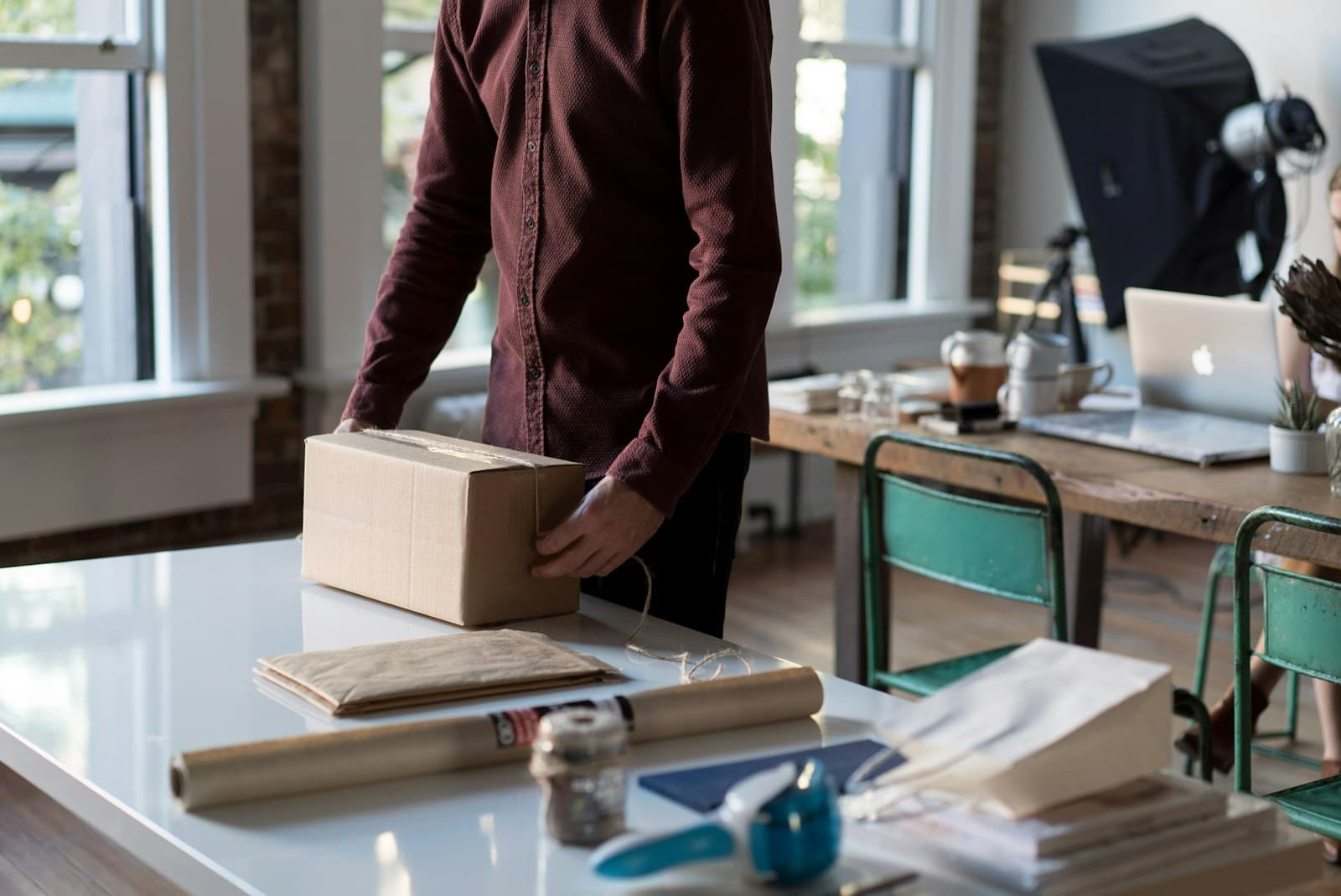 Person pakker en papkasse på et lyst arbejdsbord